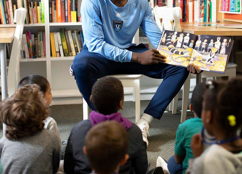 Student reading a book to children
